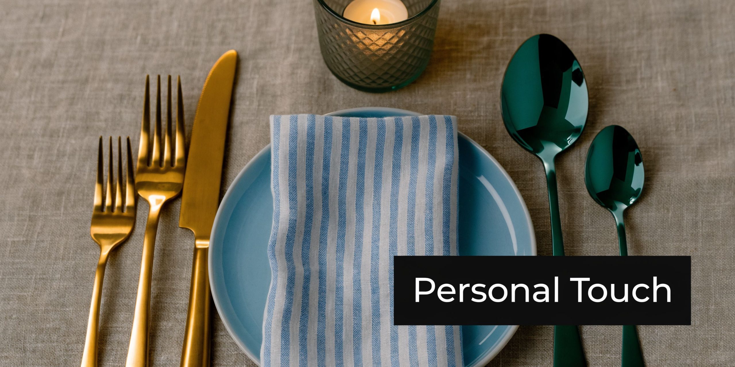A place setting with a blue plate, striped napkin, gold silverware, and green spoons on linen.
