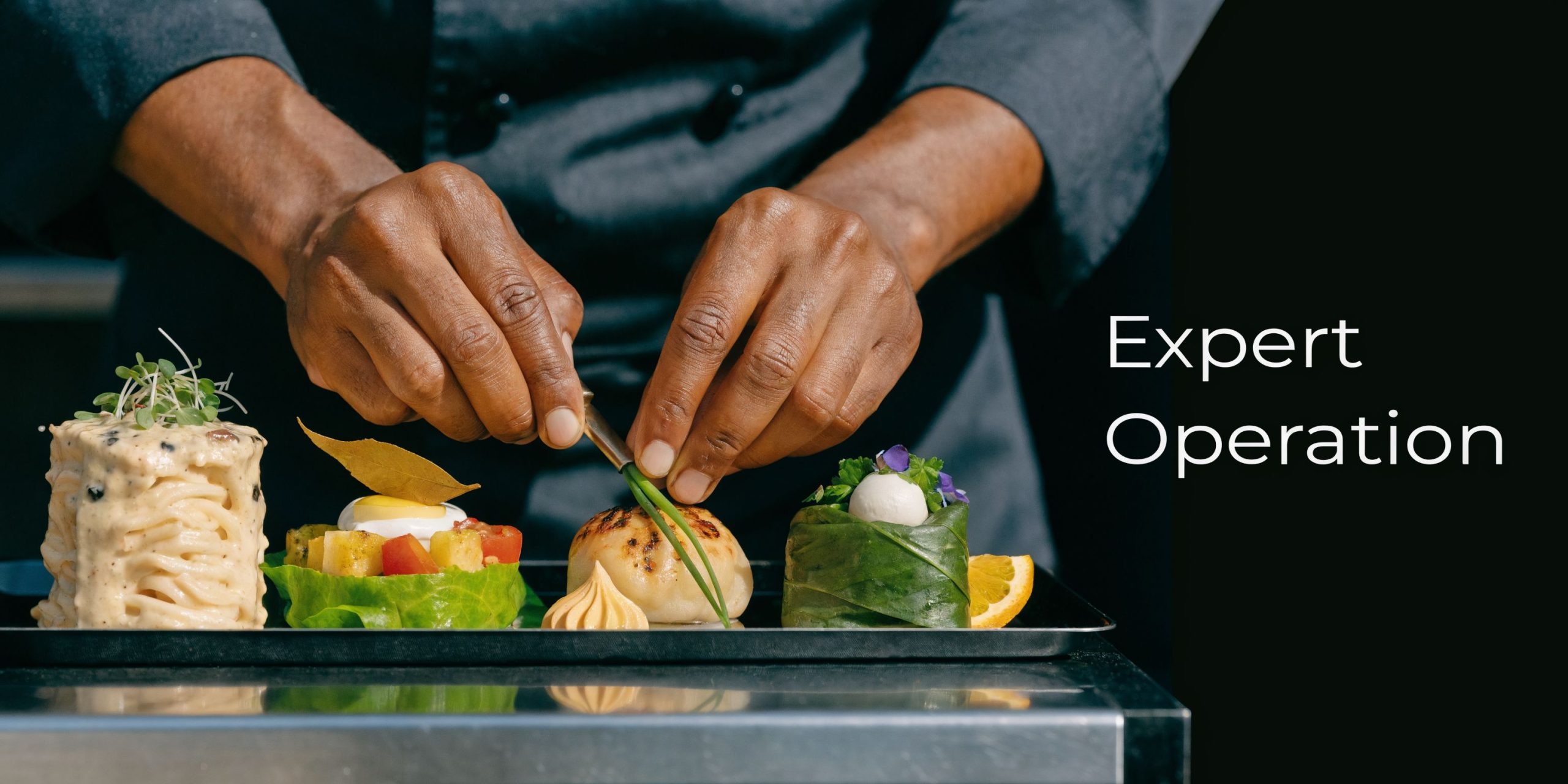 A professional chef carefully garnishes a variety of elegant gourmet dishes displayed on a sleek hot tray.