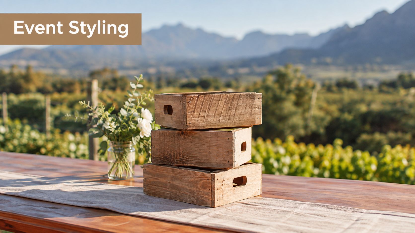 A stack of three rustic small wooden crates placed on a table with flowers in a jar.